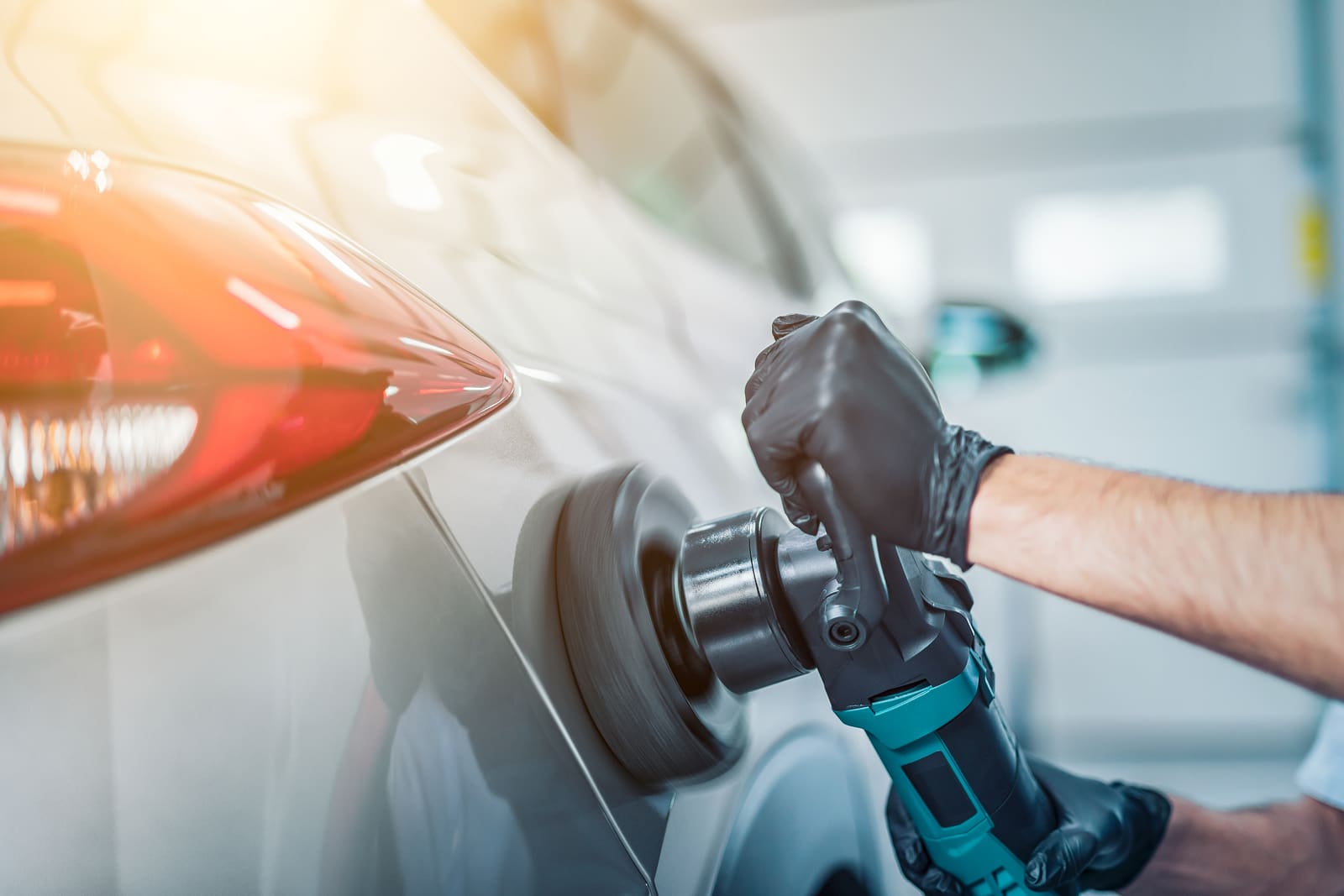 Car detailing - Man holds a polisher in the hand and polishes the car. Selective focus.