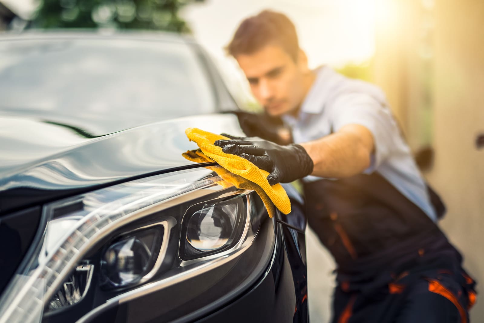 Car detailing - the man holds the microfiber in hand and polishes the car. Selective focus.